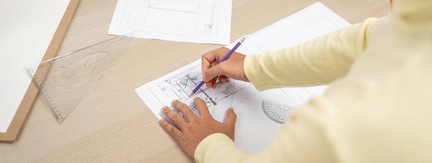 Cropped image of skilled architect designer hand draws blueprint with architectural equipment and blueprint. Creative working and design concept. Closeup. Focus on hand. Back view. Variegated. - Photo, Image