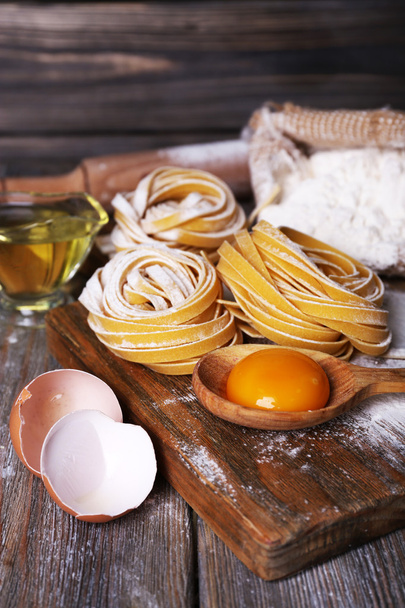 Raw homemade pasta and ingredients for pasta on wooden background - Foto, Imagen