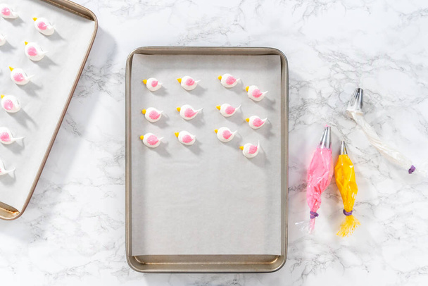 Piping meringue with piping bags into the baking sheet lined with parchment paper to bake Easter meringue cookies. - Photo, Image
