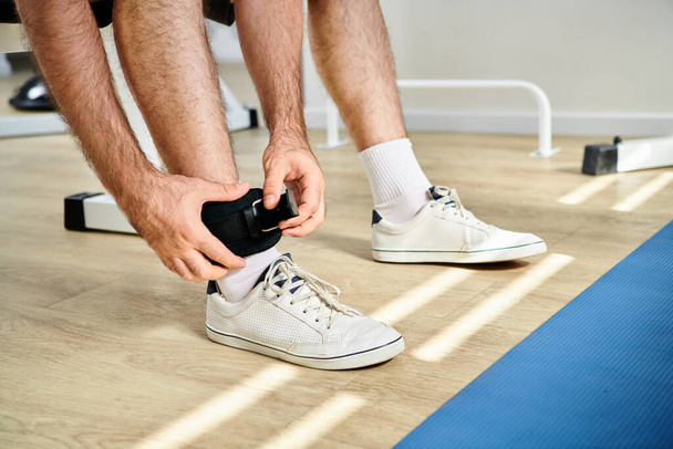 przycięty widok człowieka wprowadzenie pasa fitness nogi przed treningiem odzyskiwania w nowoczesnym centrum kinesio - Zdjęcie, obraz