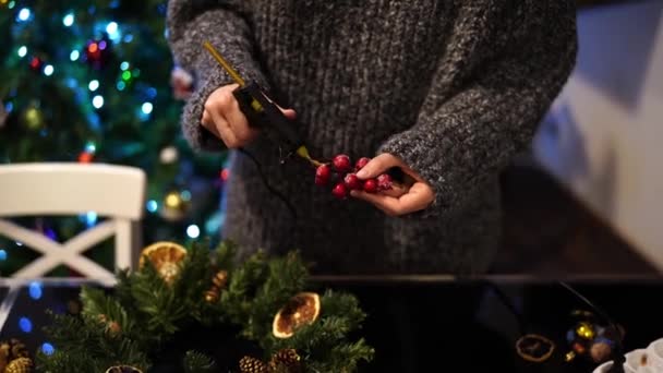 Il designer applica la colla da una pistola a un ramo di bacche durante una ghirlanda Di Capodanno. Filmati 4k di alta qualità - Filmati, video