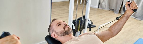 handsome man in sportswear training arms on exercise machine in kinesio center, banner - Photo, Image