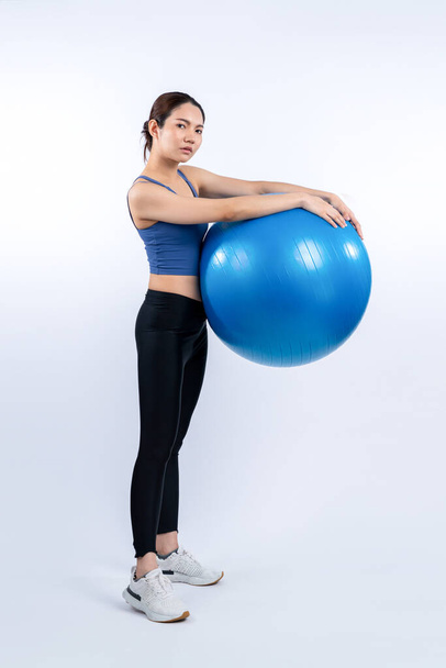 Młoda, atrakcyjna azjatycka kobieta portret w odzieży sportowej z dopasowaną piłką skierowaną na mięśnie brzucha dla skutecznego energetycznego codziennego treningu rutynowego. Zdjęcia studyjne i odizolowane tło. Energiczny - Zdjęcie, obraz