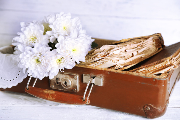 Old wooden suitcase with old books and flowers on wooden background - Фото, изображение