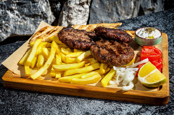 A close-up view of three cutlets served alongside a portion of golden French fries on a rustic wooden board. Ideal for food enthusiasts, culinary concepts, and mouthwatering food photography - Photo, Image