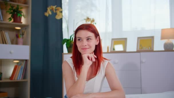 muotokuva nuori nainen siivotessaan huone, tucking valkoinen arkki nukkumisen jälkeen, hymyillen ja katsoen kameraa - Materiaali, video