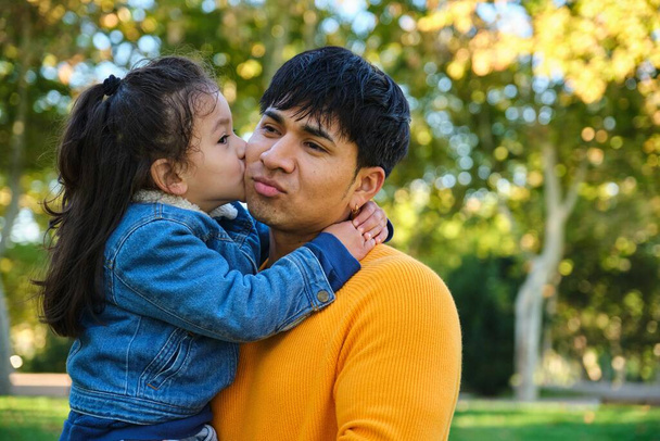 Πορτρέτο του ευτυχισμένου γιου του Εκουαδόρ που φιλάει τον πατέρα του σε ένα πάρκο. - Φωτογραφία, εικόνα
