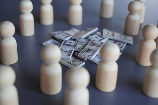 Een groep houten poppen en een stapel geld. Financiering, schenking, belegger en crowdfundingconcept - Foto, afbeelding