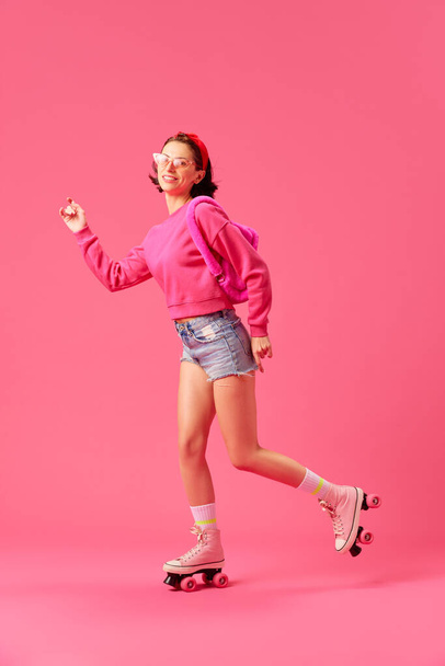 Retrato de longitud completa de la mujer joven, modelo que usa ropa de moda con accesorios rosados modernos tienen fondo de estudio vívido aislado patinaje divertido. Concepto de juventud, estilo, emociones humanas. ad ad - Foto, Imagen