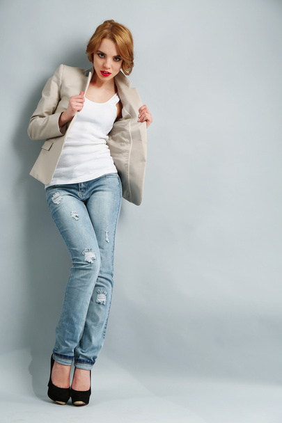 Beautiful young woman in jacket and jeans posing on light background - Photo, image