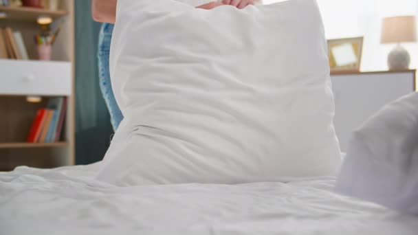 lição de casa, uma jovem mulher coloca as coisas em ordem em casa e limpa lençol branco na cama no quarto - Filmagem, Vídeo