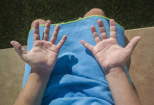 Child boy showing his wrinkled hands after swimming in the pool. Overhead view - Photo, Image