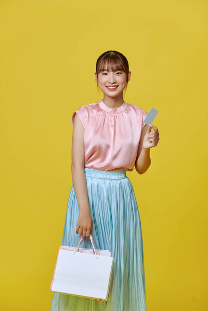 aziatische gelukkig vrouw meisje houdt kleurrijke winkelen pakketten en cashless credit card betaling - Foto, afbeelding