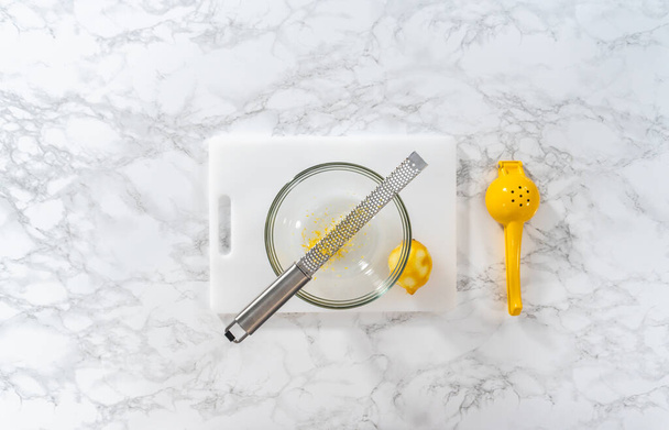 Zesting y jugo de limón fresco en una tabla de cortar blanca. - Foto, Imagen