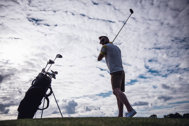 Ganztägiges Porträt eines gutaussehenden Kerls, der beim Golfspielen einen Golfschläger benutzt - Foto, Bild
