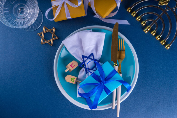 Hanuka asztal beállítása, zsidó újév ünnep meghívó vagy menü háttér tányérral, evőeszközök, ajándék doboz és hagyományos dekoráció, felülnézet, lakás laikus másolási hely - Fotó, kép