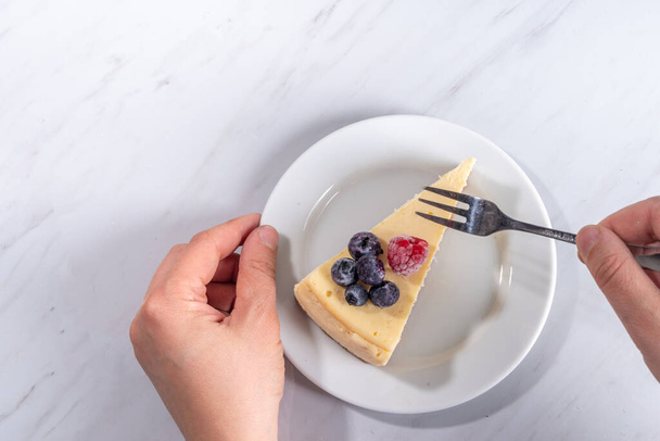 Cheesecake portion slice on plate, with raspberry on blueberry on white marble background  - Photo, Image