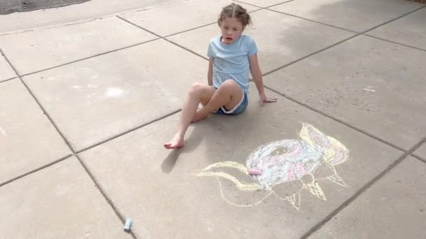 Bambina disegno gesso arte su un vialetto suburbano in una giornata estiva. - Filmati, video