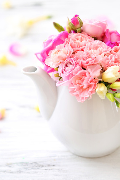 Beautiful spring flowers in teapot on wooden table, closeup - Foto, immagini