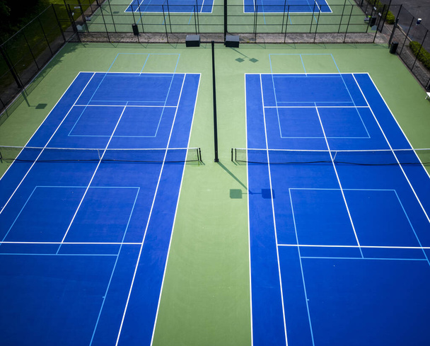 Une vue de drone regardant vers le bas les courts de pickleball de tennis bleus bordés de bleu clair pour pickleball avec des lumières. - Photo, image