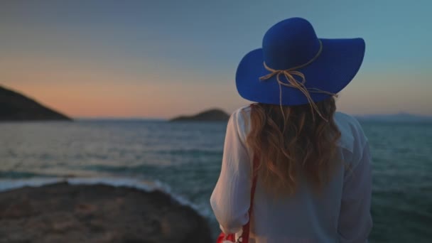 Τουριστική γυναίκα με μπλε καπέλο δίπλα στη θάλασσα. - Πλάνα, βίντεο