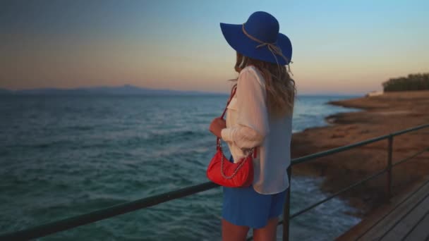 Turistická žena v modrém klobouku u moře. - Záběry, video