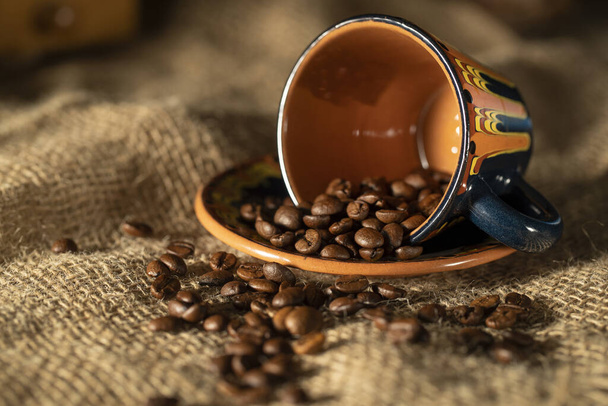 Tazza di caffè in ceramica e chicchi di caffè sul tavolo - Foto, immagini
