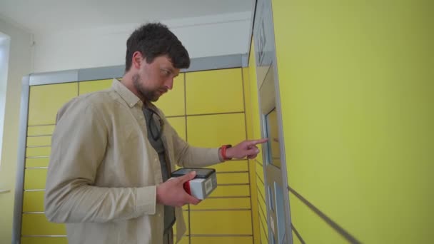 Ο άνθρωπος χρησιμοποιεί κίτρινο σταθμό συσκευασίας για να στείλει το πακέτο με self-service. Γερμανικό πακέτο και τερματικό παροχής υπηρεσιών παράδοσης. Τύπος αποστολέα tracking label στο κίτρινο κέντρο συσκευασίας στην Deutschland και αποστολή πακέτου.  - Πλάνα, βίντεο