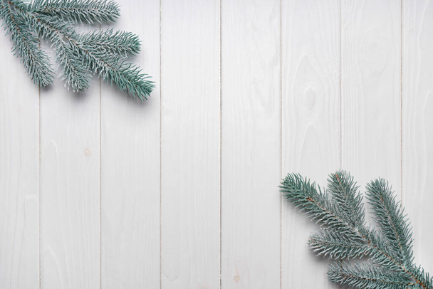 Snowy Christmas fir tree branches on white wooden board background top view, flat lay. Banner, header, wallpaper, backdrop with copy space.  - Photo, Image