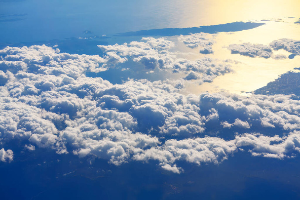 Zapierająca dech w piersiach panorama, jak samolot wznosi się nad morzem rozległych chmur. Blask słońca, chmury pod samolotem rzucają dramatyczne cienie - Zdjęcie, obraz