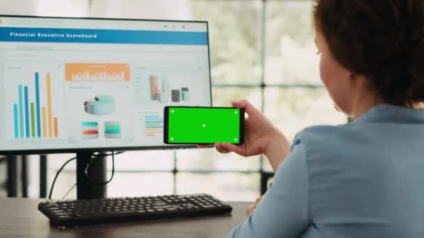 Бізнес-спеціаліст показує зелений колір на дисплеї програмного забезпечення смартфона, дивлячись на ізольований шаблон хромосоми і працюючи на комп'ютері за столом. Використання порожніх макетів і операцій фінішного агентства. - Кадри, відео