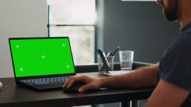 Mężczyzna pracownik patrzy na zielonym ekranie chromakey wyświetlacz, podczas gdy siedzi w kreatywnej agencji roboczej, pracując nad operacjami e-commerce. Profesjonalny analityk sprawdza pusty układ makiety na laptopie. - Materiał filmowy, wideo