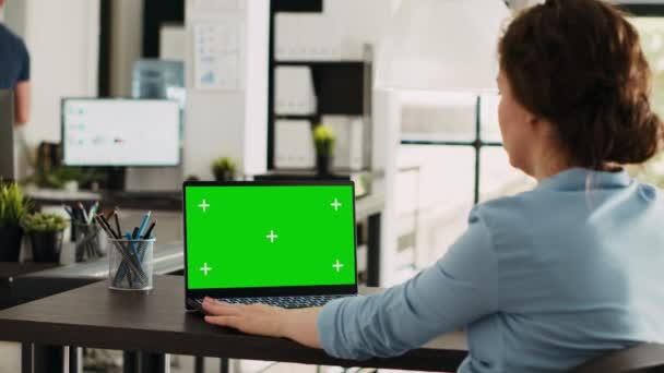 Ofis masasında dizüstü bilgisayarında yeşil ekran ile çalışan yönetici, model krom anahtar görüntüsünü ve izole edilmiş telif alanı şablonunu analiz ediyor. İş yerinde kişisel bilgisayar kullanan bir kadın. - Video, Çekim