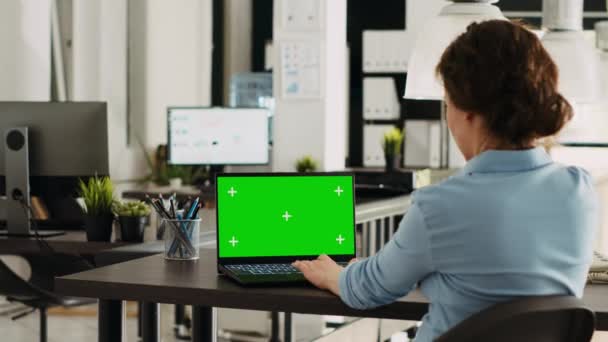 Specialista používající notebook se zelenou obrazovkou k řešení obchodních úkolů a operací v kanceláři, při pohledu na chromakey displej v kooperačním prostoru. Žena pracující na bezdrátovém PC s copyspace. - Záběry, video