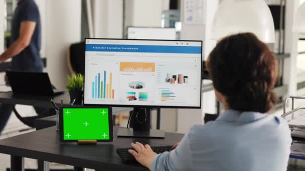 İş kadını, bilgisayardaki gelir verilerini analiz ederken izole edilmiş bir telif alanı şablonuna bakarak, modern tablette sunulan yeşil ekran ile masada çalışıyor. İşçi kromakey ekran kullanır. El kamerasıyla.. - Video, Çekim