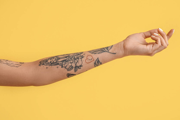 Tetovált női kéz sárga háttér - Fotó, kép