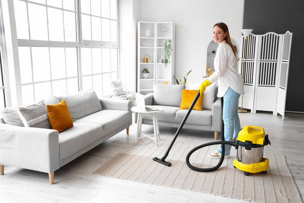 Young woman hoovering carpet at home - Photo, Image