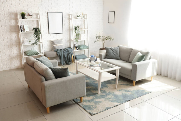 Interiér světlého obývacího pokoje s útulnými šedými pohovkami a konferenčním stolkem - Fotografie, Obrázek