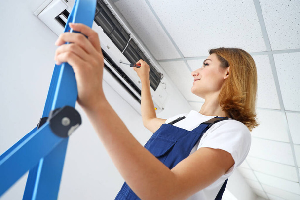 Nainen teknikko vahvistamisesta ilmastointilaite huoneessa - Valokuva, kuva