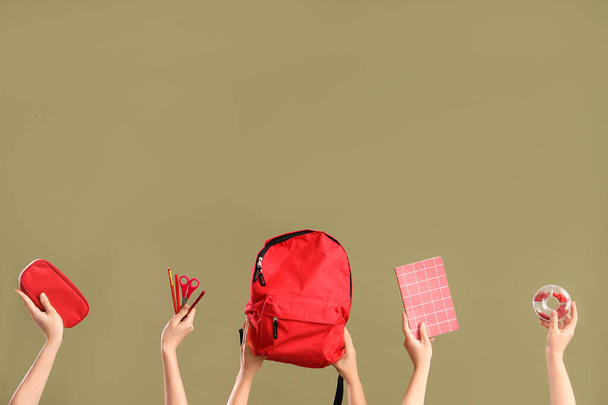 Багато рук з шкільними приладдям та рюкзаком на кольоровому фоні - Фото, зображення
