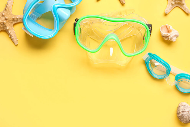 Máscaras de natación, concha marina y estrellas de mar sobre fondo amarillo - Foto, imagen