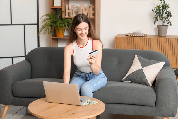 Young woman with credit card using laptop at home - Photo, Image