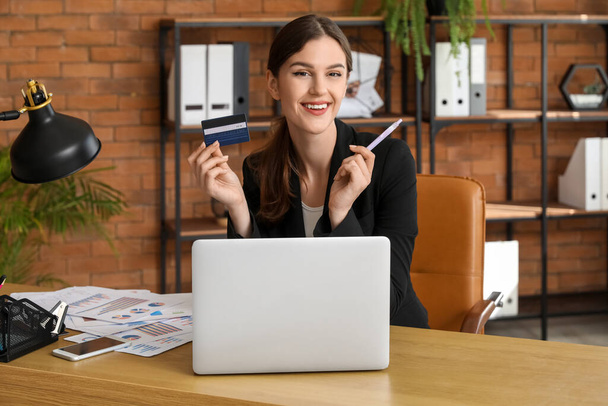Νεαρή επιχειρηματίας με πιστωτική κάρτα στο τραπέζι στο γραφείο - Φωτογραφία, εικόνα