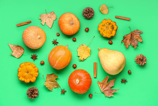 Zucche fresche con diverse spezie, castagne e foglie autunnali su sfondo verde - Foto, immagini