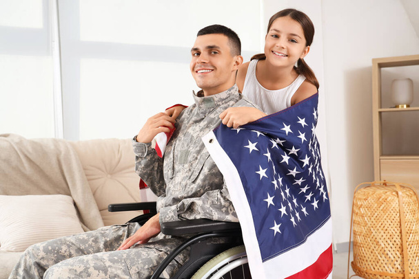 Στρατιώτης σε αναπηρικό καροτσάκι και η κορούλα του με τη σημαία των ΗΠΑ στο σπίτι. Ημέρα των Βετεράνων - Φωτογραφία, εικόνα