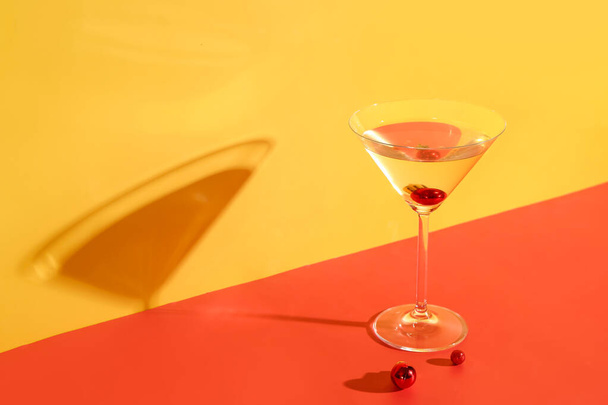 Glas Cocktail mit Weihnachtskugeln auf farbigem Hintergrund - Foto, Bild