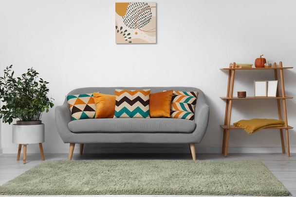 Wnętrze nowoczesnego salonu z szarą sofą, poduszkami i roślinnością - Zdjęcie, obraz