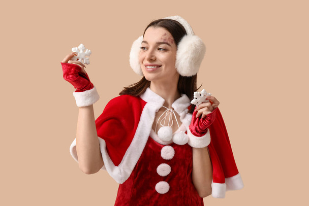Mulher bonita vestida de Papai Noel com flocos de neve decorativos em fundo bege - Foto, Imagem