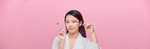 Atractiva asiática joven modelo mostrando natural maquillaje rutina y pintura pestañas - Foto, imagen