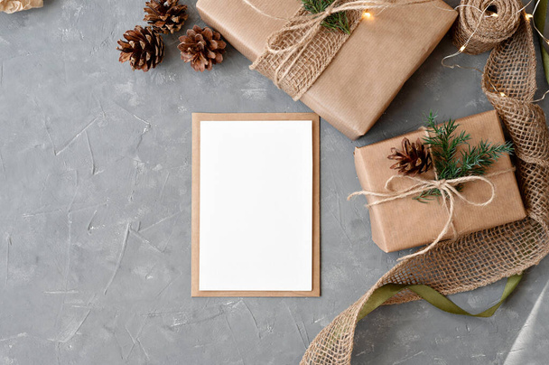 Esztétikai karácsonyi ünnepség koncepció, skandináv stílus. Üres papír mockup, boríték, ünnepi ajándékok az asztalon. Üzleti márka vagy blog sablon. - Fotó, kép